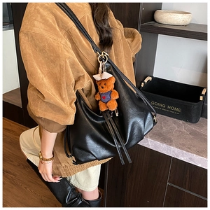 Close-up of black pleated dumpling bag with soft PU leather and cute bear charm detail