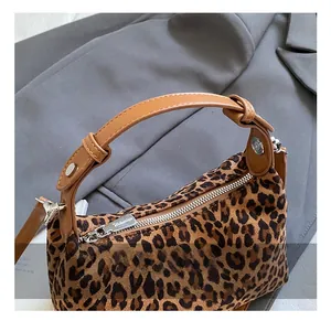 Detailed close-up of leopard print handbag texture with leather handle and metal hardware