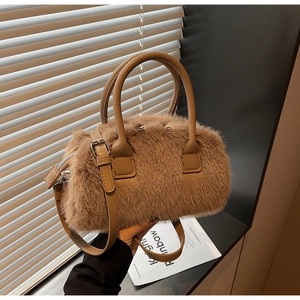 Detailed texture of warm brown plush Boston bag with leather handles and silver zipper