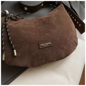Détail du sac à main en daim marron foncé avec rivets et breloques en perles de bois