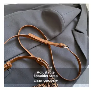 Detail of adjustable brown leather shoulder strap with metallic buckle for handbag