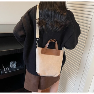 Detail of canvas tote bag featuring brown leather trim and adjustable wide fabric strap