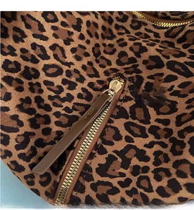 Detailed macro view of the gold metal zipper and leopard print suede fabric texture