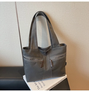 Detail of dark grey canvas tote bag with front zipper pockets on decorative books