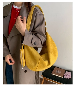 Detail of yellow suede dumpling bag with small zip pouch shown in a lifestyle setting