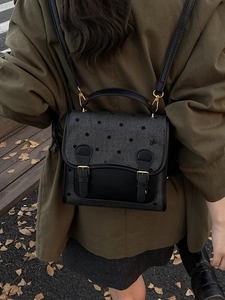 Chic dark grey polka dot backpack with black leather flap and gold buckle details