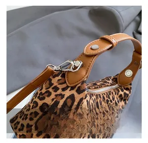 Close-up of leopard print bag showing silver metal hook and brown leather strap detail