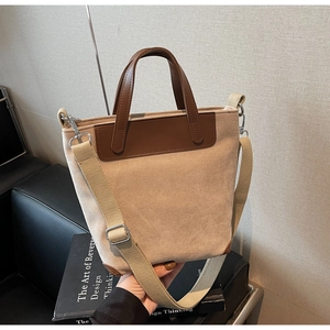 Detail of minimalist canvas tote bag with brown leather trim and wide shoulder strap