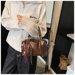 Vue détaillée du sac Boston en cuir ciré marron avec des charms décoratifs tressés