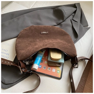 Vue de dessus de l'intérieur spacieux d'un sac en daim marron avec essentiels du quotidien