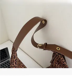 Detail of leopard print suede bag showing the adjustable leather strap and gold buckle