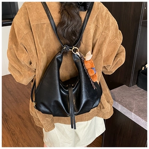 Close-up of black pleated leather backpack with tassel zipper and brown bear pendant