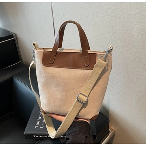 Detail of minimalist tote bag with brown leather handles and adjustable wide strap