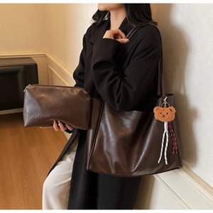 Detail of dark brown leather tote bag set with matching pouch and plush bear charm