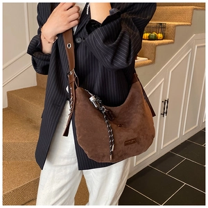 Détail du sac hobo en daim marron foncé avec breloque en corde tissée et bandoulière
