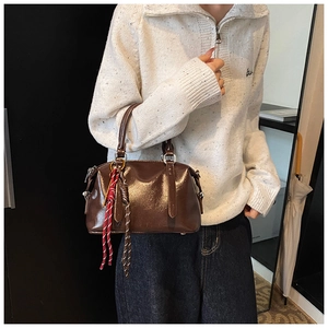 Détail d'un sac Boston en cuir ciré marron avec des breloques en corde tressée