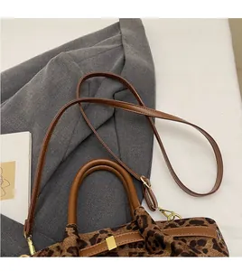 Detail der Leoparden-Beuteltasche mit braunen Ledergriffen und goldenen Metallbeschlägen