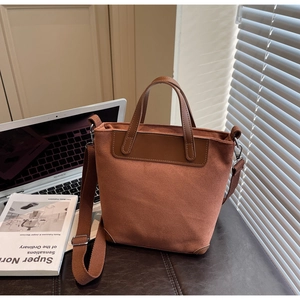 Detail shot of a brown suede tote bag with leather straps and an adjustable shoulder strap