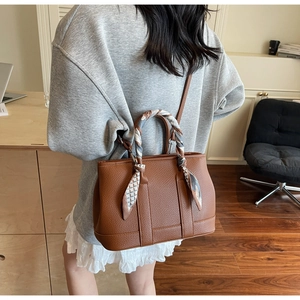Brown lychee leather bucket bag detail with geometric silk scarf wrapped around handle
