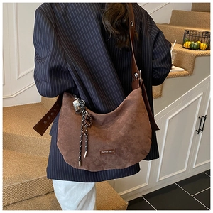 Gros plan du sac hobo en daim marron avec bandoulière réglable et patch décoratif