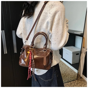 Détail du sac Boston en cuir marron vintage avec clé dorée et sangle tressée