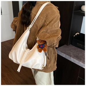 Close-up of off-white hobo bag with soft faux leather texture and brown bear pendant