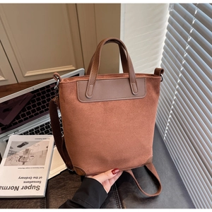 Detail view of brown suede tote bag featuring smooth leather trim and adjustable strap