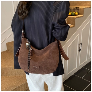 Détail du sac hobo en daim marron foncé avec forme de lune et étiquette en cuir