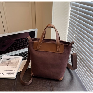 Detail of dark brown suede tote bag with leather handles and detachable shoulder strap