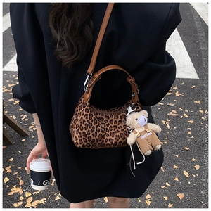 Detail of leopard print half-moon crossbody bag with cute plush bear charm accessory