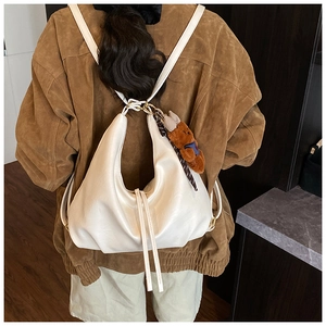 Detailed view of white pleated leather bag with drawstring and cute bear charm