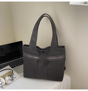 Detail of dark grey canvas tote bag with dual front zippers and brown leather pulls