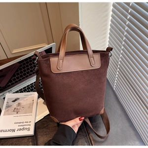 Detail of dark brown suede shoulder bag with leather trim and adjustable fabric strap