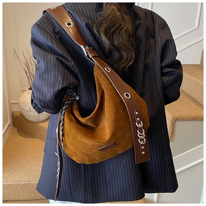 Détail du sac hobo en daim marron avec anneaux argentés et bandoulière à œillets