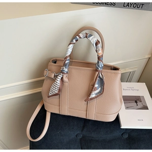 Detail of light brown lychee grain leather bucket bag with silk scarf on handle