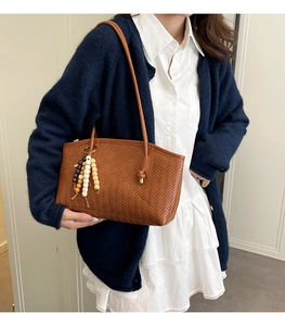 Detailed close-up of brown woven texture tote bag with colorful wooden bead tassel