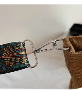 Close-up of vintage patterned woven strap with polished metal clasp on canvas bag