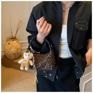 Detailed close-up of leopard print handbag with a cute teddy bear charm accessory