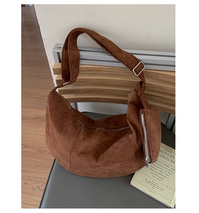 Detailed macro shot of dark coffee suede crescent bag with silver zipper and side pocket