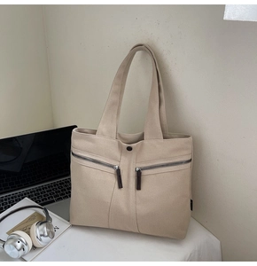 Detail of beige canvas tote bag with double zipper pockets in a lifestyle setup
