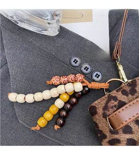 Detailaufnahme des bunten Holzperlenanhängers mit Metallclip an einer Handtasche mit Leoprint