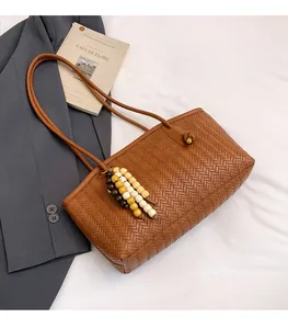 Close-up of brown woven tote bag with wooden bead tassel and retro faux leather texture