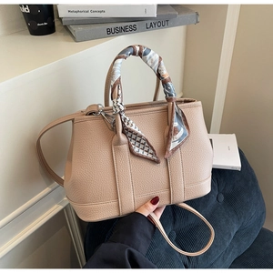 Detail of beige lychee grain leather tote bag with printed silk scarf on handle