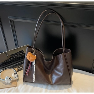 Detailed view of deep brown tote bag with bear charm and urban commute essentials