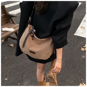 Sac hobo en daim marron avec breloque tressée et étiquette mode sur fond de rue urbaine