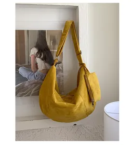 Detail of yellow crescent shoulder bag with suede texture and matching mini pouch accessory