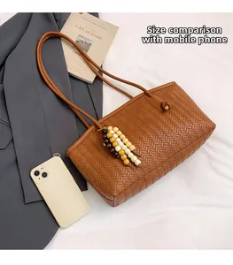 Dark brown woven tote bag size comparison with a smartphone and fashion accessories