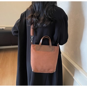 Detail of caramel suede bucket bag showing texture and adjustable fabric shoulder strap