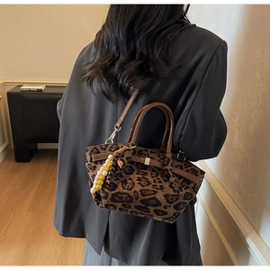 Detail of leopard print bucket bag with leather handles and decorative beaded tassel