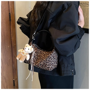 Detail of leopard print handbag with black strap and cute teddy bear charm pendant